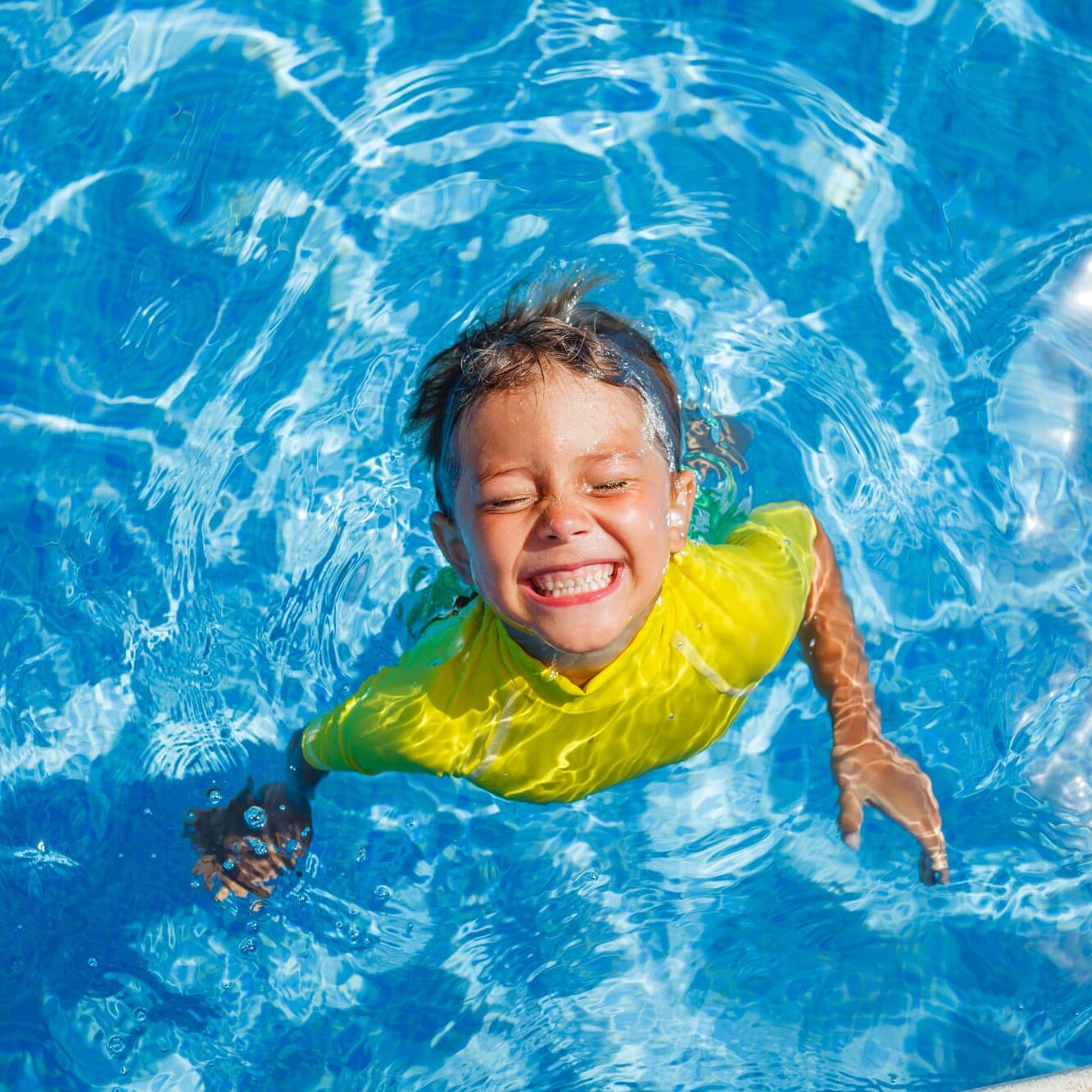 Cute happy little boy swimming and snorking in the swimming pool