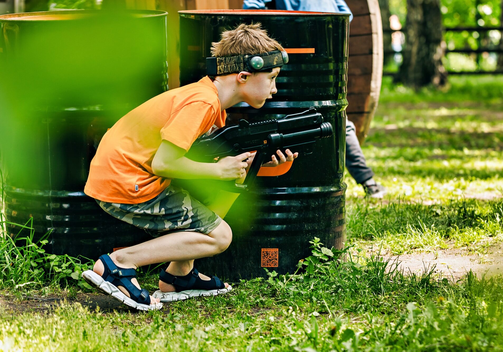 armed teenager boy playing in laser tag shooting game outdoors