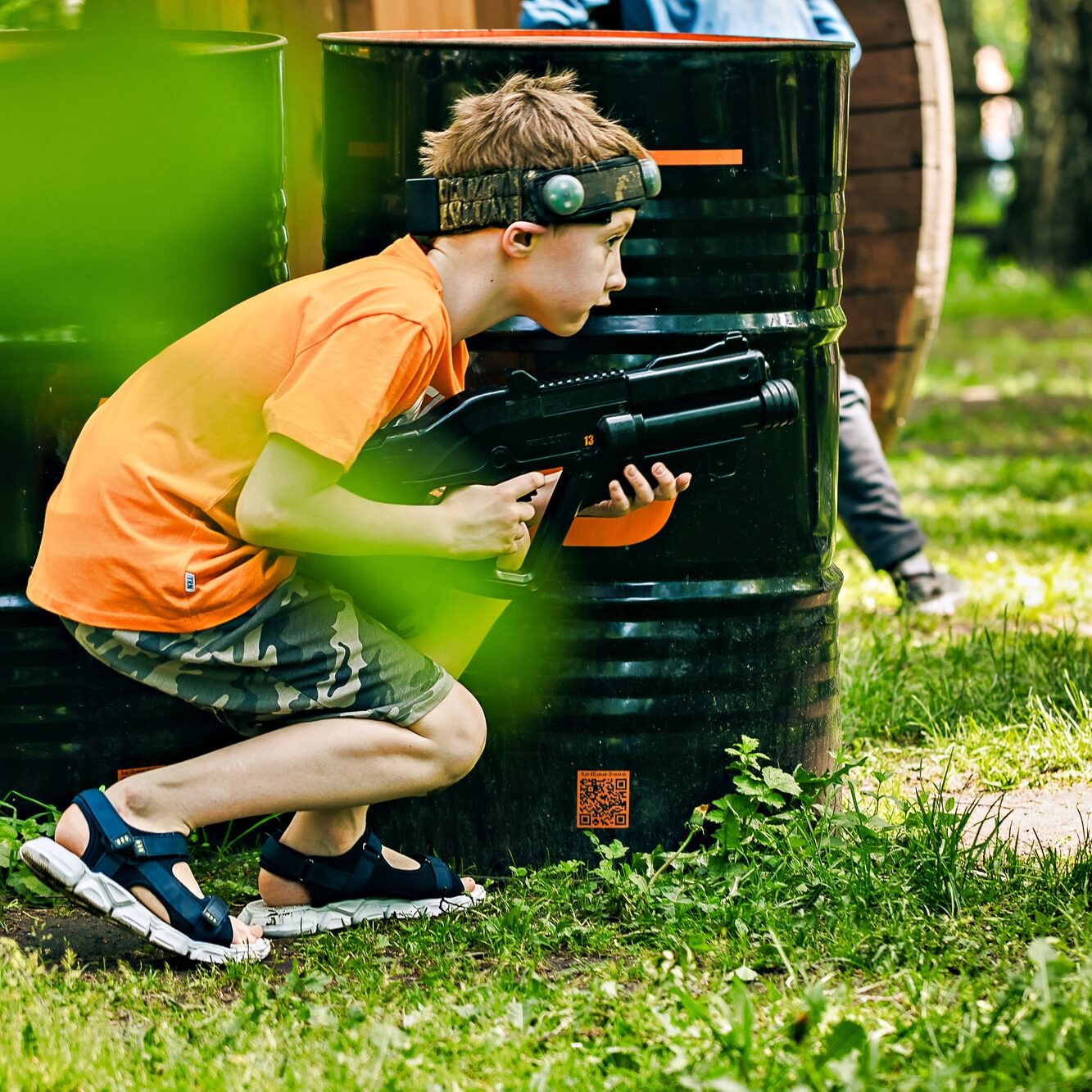 armed teenager boy playing in laser tag shooting game outdoors